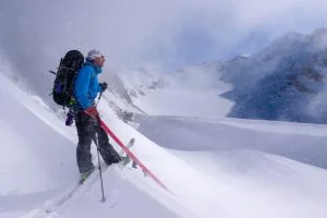 En person med passion för skidåkning på toppen av ett berg i dåligt väder.